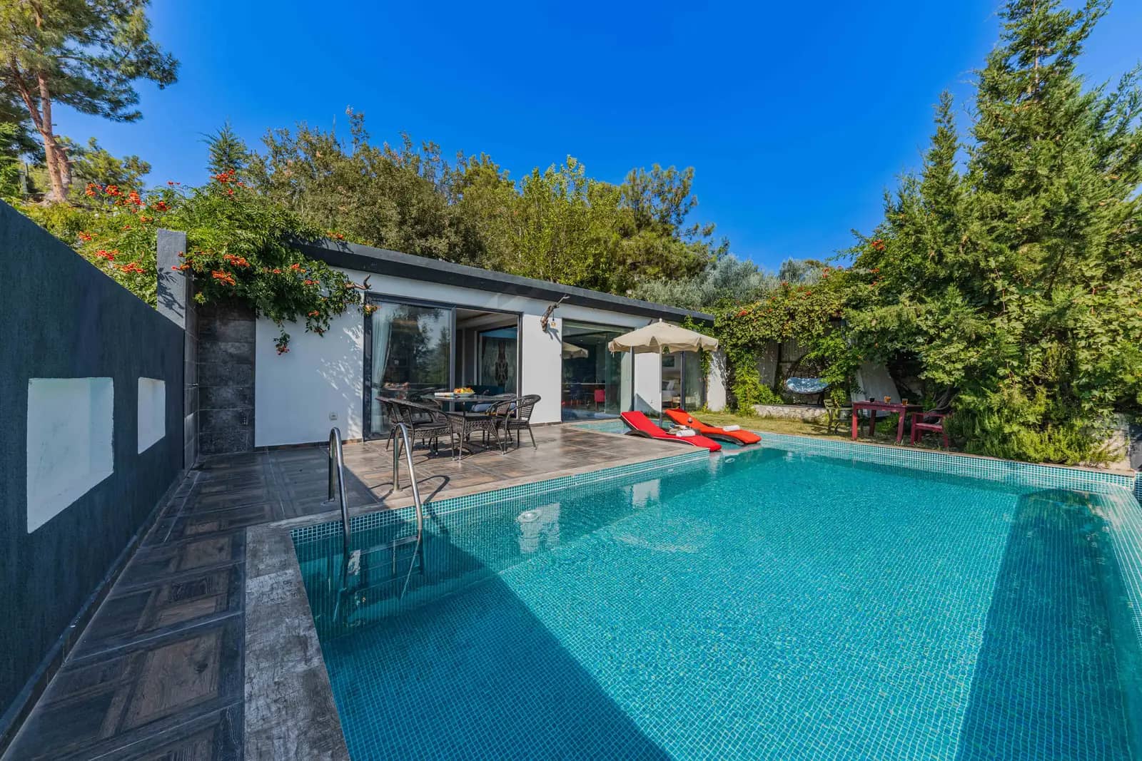 Villa pool with clear turquoise water beside a shaded garden terrace